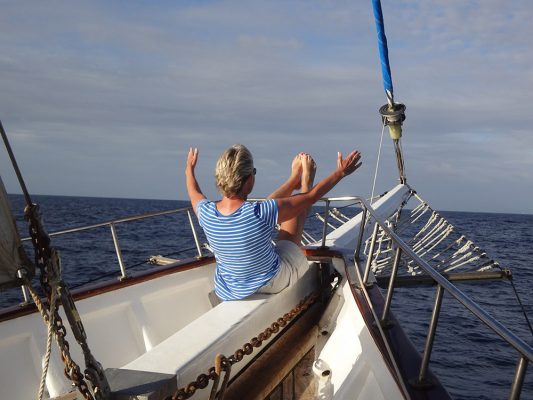 Femme faisant une extension pilates sur l'avant d'un voilier