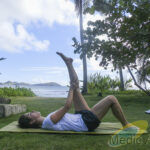 Méthode Pilates : pourquoi un tel succès ? Femme faisant un étirement pilates dans un jardin face à la mer